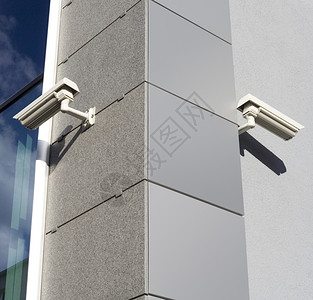 警卫智力私人的大楼拐角上贴有安全摄像头背景图片
