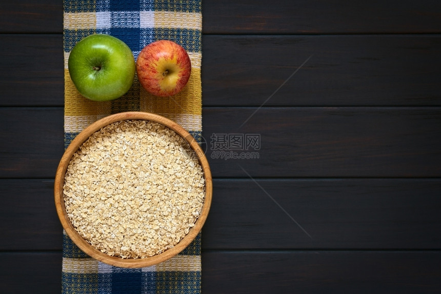 木碗中生滚燕麦布上苹果用天然光照在黑木上甜点厨房早餐图片