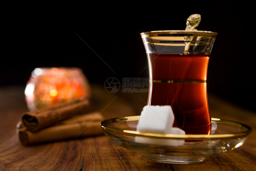 芳香金属黑色的传统玻璃中土耳其茶的特写背景为传统玻璃中背光土耳其茶的木质背景图片