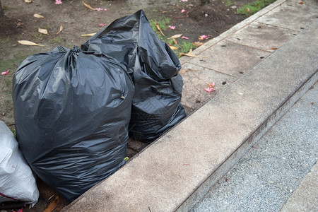 黑垃圾袋放置在公园的走道上人行肮脏的走廊图片