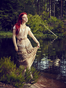 穿着裙子的迷人年轻女站在水线边背面湖身着洋装摆姿势胡萝卜成人图片