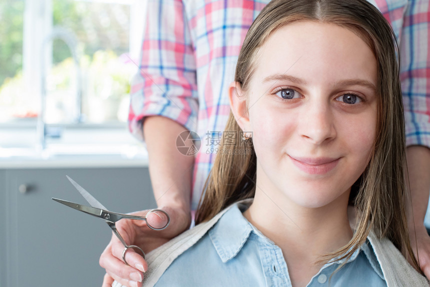 社会的白种人青少年禁闭期间在家中剪掉少女儿头发的母亲肖像图片