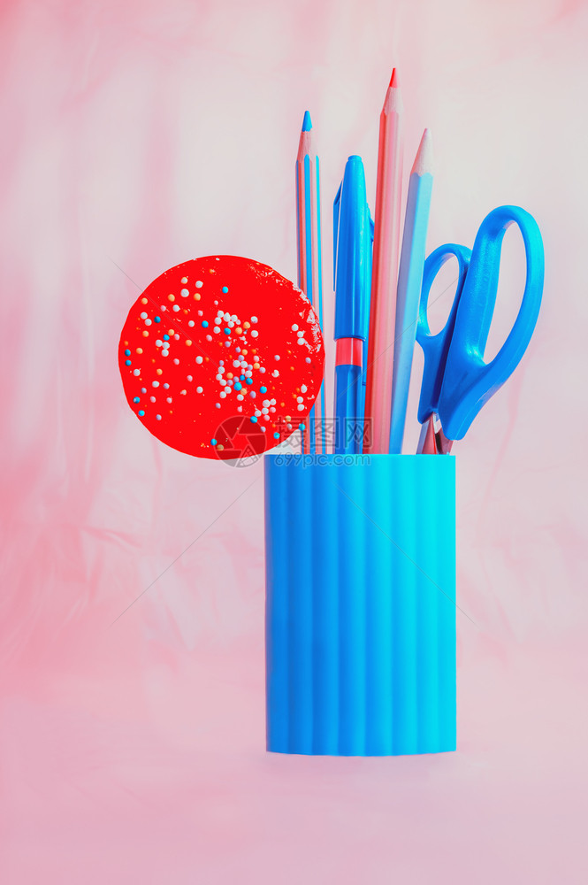 粉色的材料盒子蓝铅笔配有剪刀和红圆糖的蓝铅笔箱放在粉底背景上图片
