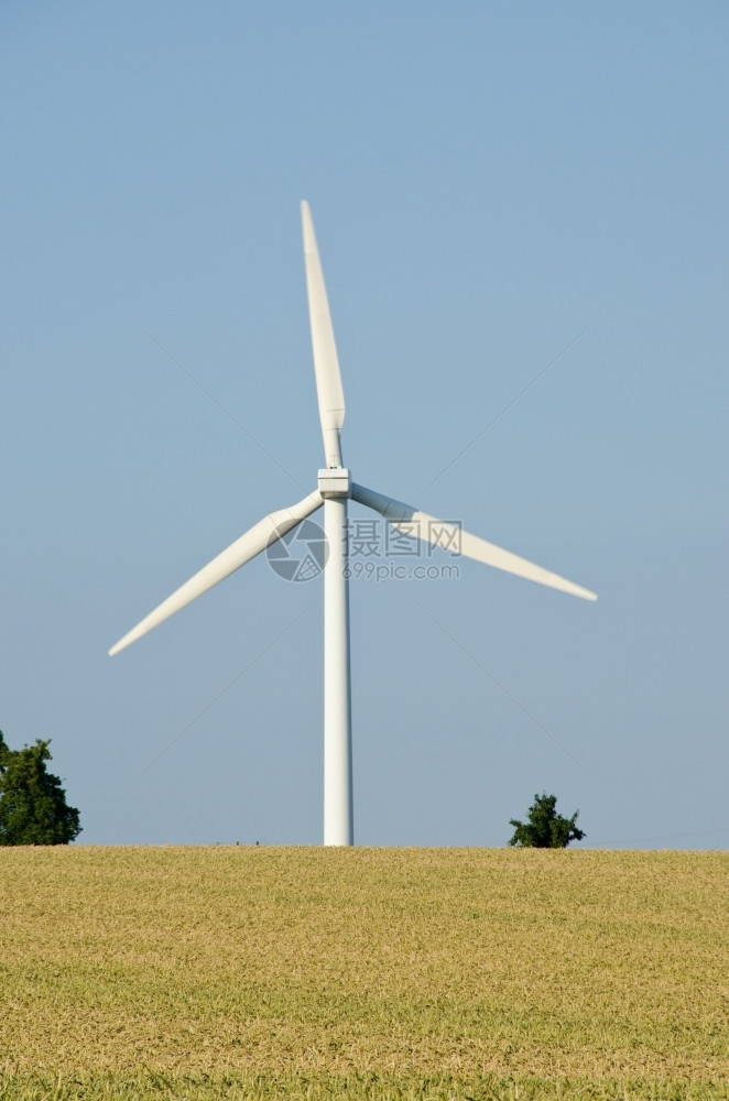 技术旋转从后面观察到的风力涡轮机磨涡轮机对蓝天空和浅地小麦田进行打击回转图片