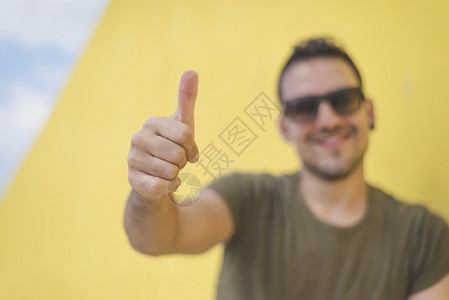 工人一个快乐的年轻男子肖像显示好姿态孤立在黄色背景上太阳镜灰色的微笑高清图片素材