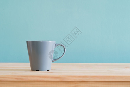 茶产品棕色木头桌上的咖啡杯和蓝色壁纸上带复制空间的布质背景休息图片
