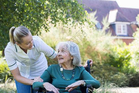 禁用成人在花园的轮椅上推车女年长妇过程图片