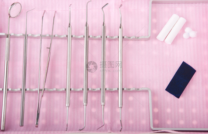 托盘中的牙科口腔包放在粉红色胸边外科器械讲义纸棉花卷和羊毛上卫生保健插件专业的图片