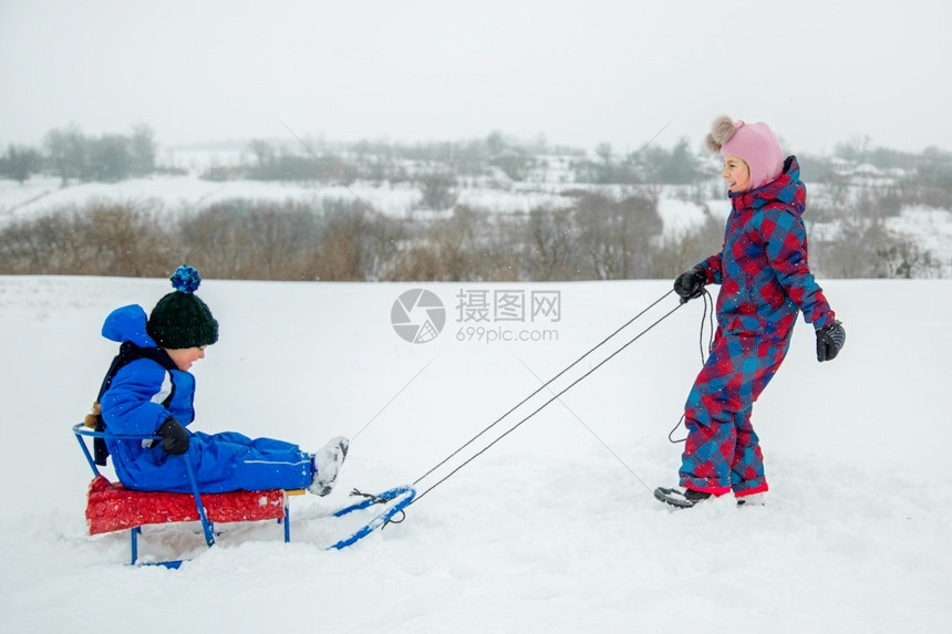 松弛快乐的男孩和女在冬天从山上拉雪橇冬季户外运动会寒假快乐的男孩和女在冬天从山上拉雪橇冬季户外运动会帽子假期图片