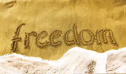 质地黄沙上刻着FREEDOM海浪季节高清图片