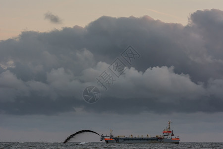 天空大部分海上有雷电罐头的吸尘机疏浚挖泥船背景