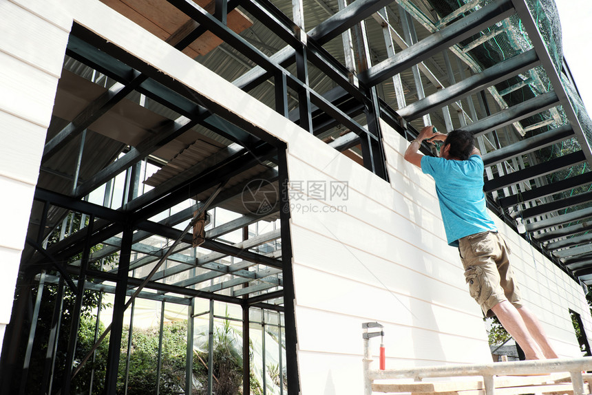外部你自己越南男子站在脚手架上智能木板打螺丝钉到铁房子框架男自己做一个房子越南达拉特外套图片
