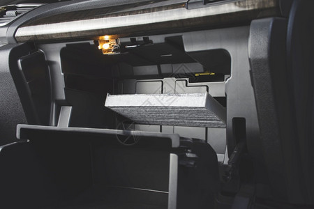 白色的代替汽车空调过滤器将其放在汽车内文件储存箱后方的空气过滤槽上在车内存放文件的隔间后面车辆背景图片