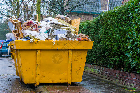 行业离开倾倒装满散废物垃圾堆回收利用概念的大型集装箱图片