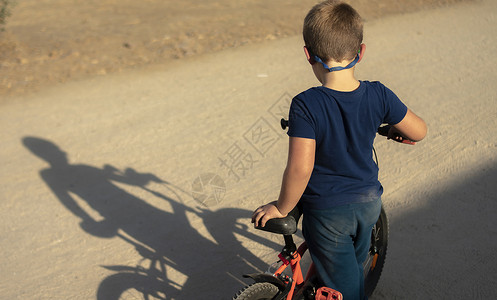 一个男孩骑着自行车在公园玩耍发现自己的影子运动服玻璃肮脏的图片