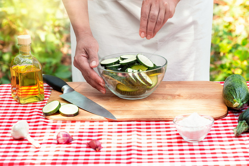烹饪自然生态友好的菜盘概念烹饪盐在透明的碗中切除松奇尼和苏在透明的碗中切除松奇尼和Zucchini之间的食盐切片一种吃图片