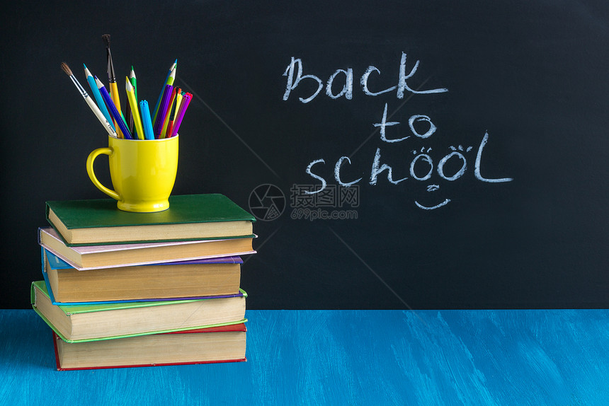 放将学校教书写回概念教育课本工作场所学生书在背景黑纸板表上的蓝色格工作场所学生书文具图木制的图片