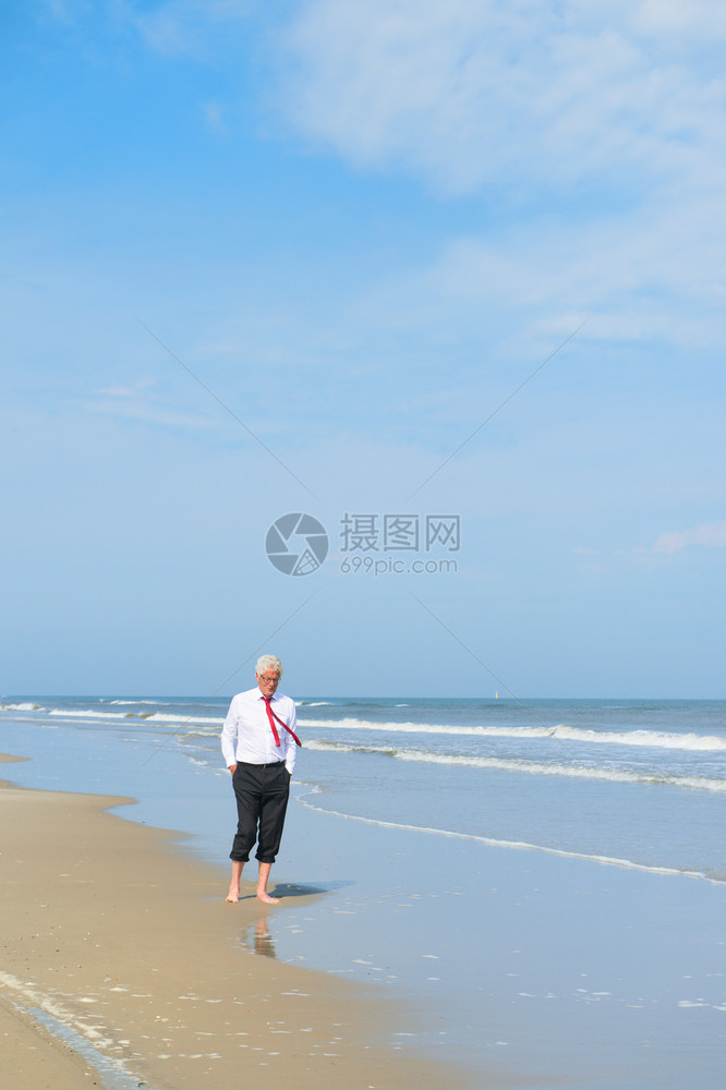 北穿正式西装的商人在海滩散步景观夏天图片