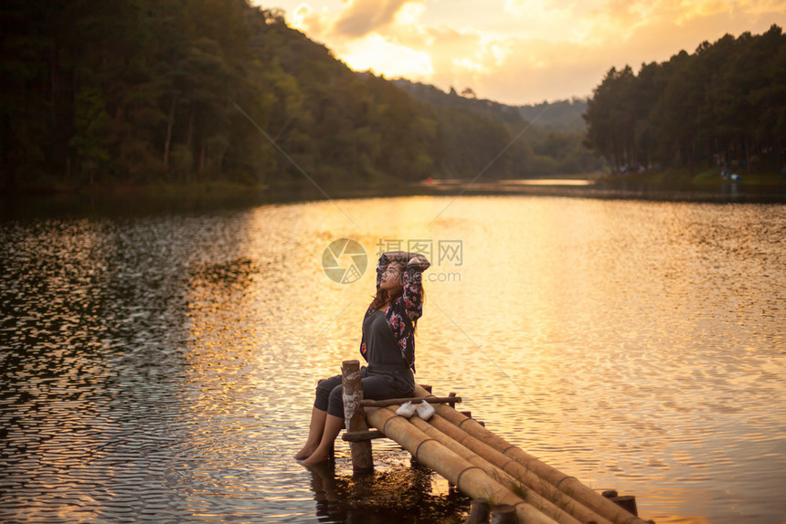 木制的坐在码头上女人看着日落的美丽放松夏天图片