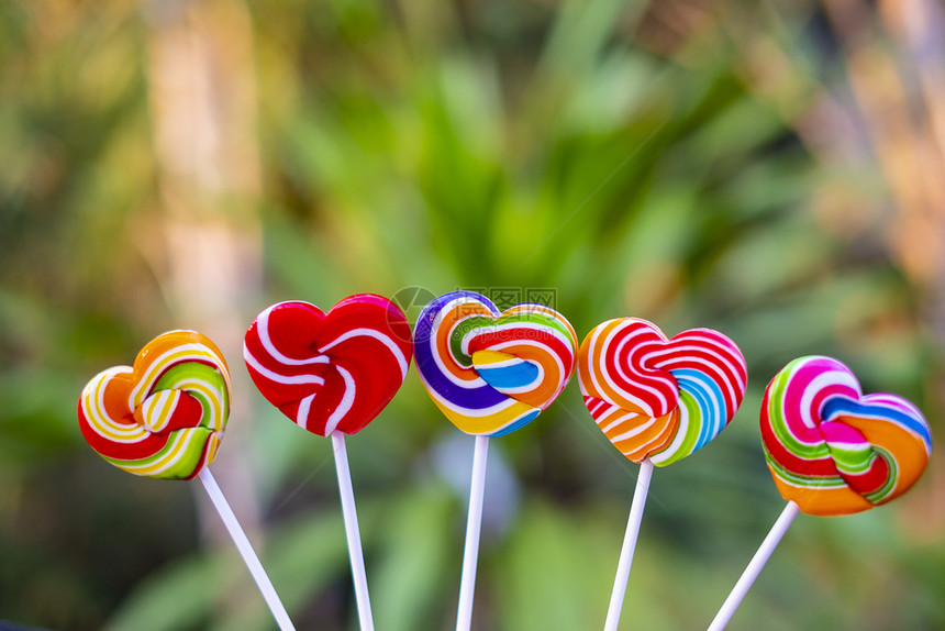 甜糖的心形状在模糊背景上满的颜色彩虹棒糖的果情人节礼物爱的概念为了红色的质地图片