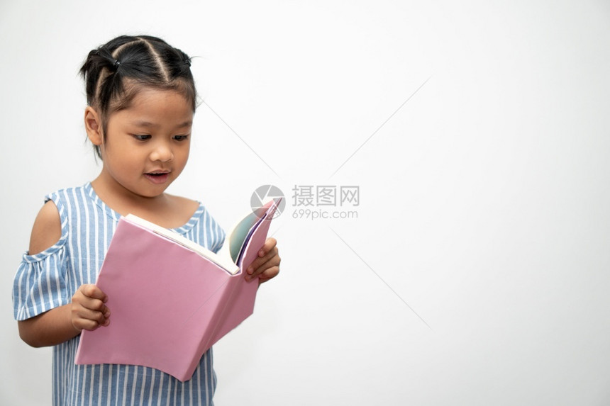 快乐的亚洲学龄前小女孩持有和阅读一本关于白人孤立背景的书学童概念与小和前班教育的概念AppyAsiaLittleStrew愉快故图片