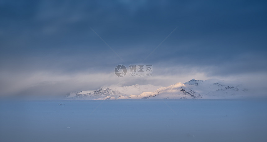 景观山美丽在日益扩大的射程上冰岛冬季日高空覆盖的天和积雪覆盖的土地上阳光照亮了明晨图片