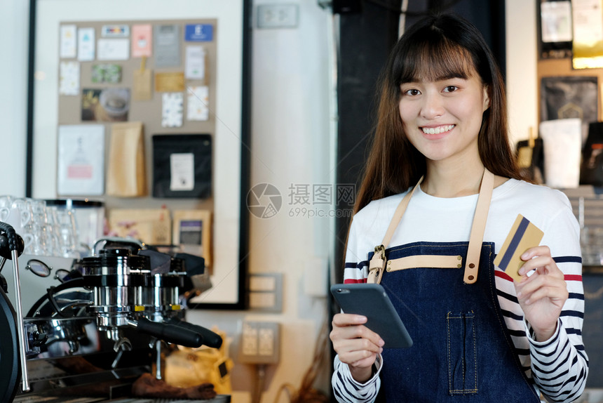 利用智能电话和在咖啡柜台持有信用卡食品和饮料商业概念的年轻亚洲女青咖啡会店铺支付成人图片