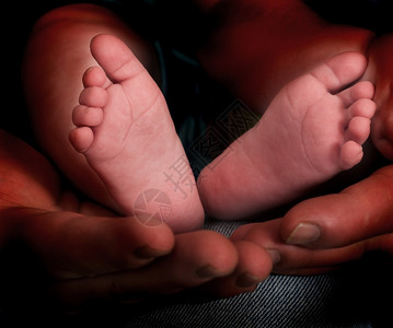 父亲的手捧着婴儿的脚图片