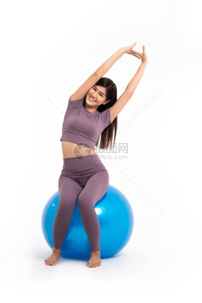 坐在瑜伽球上拉伸的年轻女子图片
