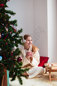 年轻女孩在清晨通过耳机听圣诞颂歌时的耳机传统家移动图片