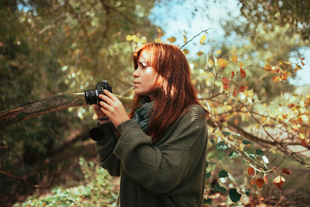 随意的户外年轻女子用旧的模拟相机在森林里拍照请享用远足高清图片素材