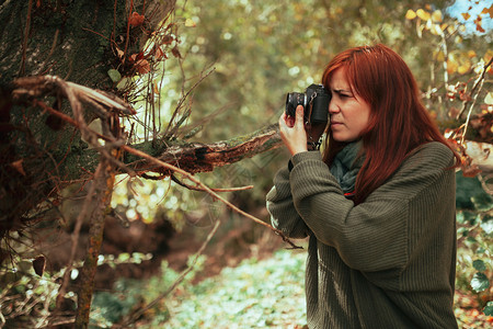 春天年轻女子用旧的模拟相机在森林里拍照下午服用自然高清图片素材