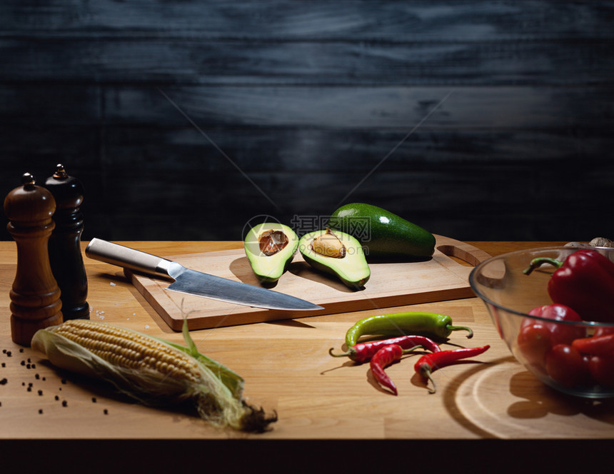 新鲜的服务在木板上用刀子低键灯光照亮桌边一些蔬菜以及复制空间将所有成熟和的鳄梨放在木板上并配有一把小刀顿饭图片