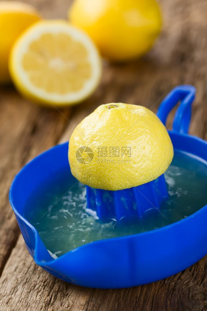 水果酸蓝柠檬或挤压器的一半背面有柠檬在木材选择焦点上拍照将柠檬一半放在边另半放在杯上目的图片
