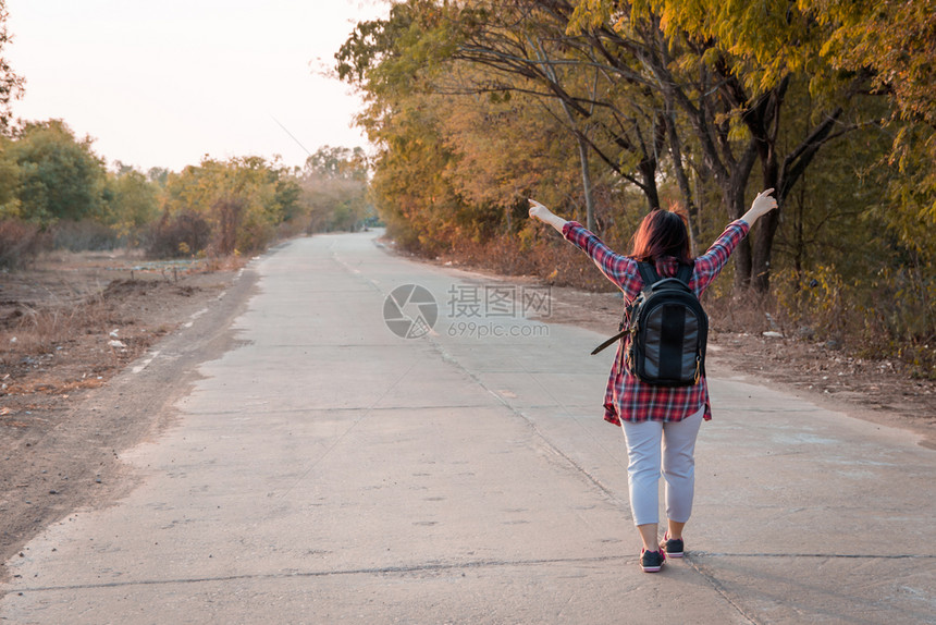徒步旅行漂亮的肖像带背在沥青路农村地区行走的女旅妇图片