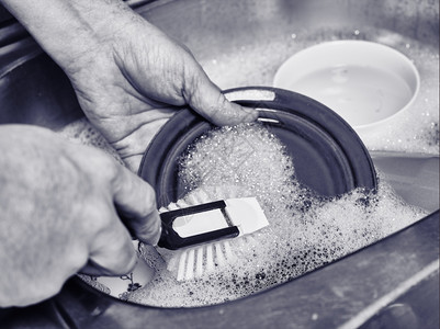 洗碗碟黑色的每天紧贴近身人用手洗盘子漆黑和白色图像图片