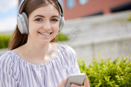 女孩在校园户外戴耳机听音乐图片