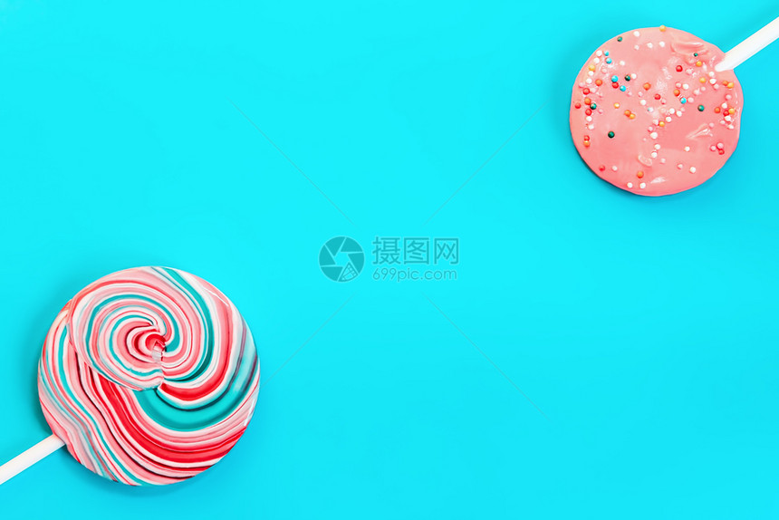 双色粉红和蓝糖果在绿松石背景上配有复制版面空间的五彩背景蓝色与两盘糖果相仿食物对角线白色的图片