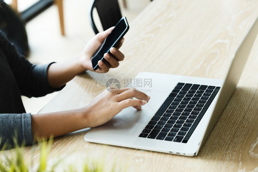 现代的触碰小工具妇女在办公室桌上使用笔记本电脑和智能话图片