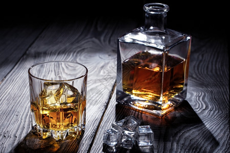 运动旧威士忌杯和木制桌上的废玻璃和拆石机旧威士忌杯和拆土机朗姆酒图片