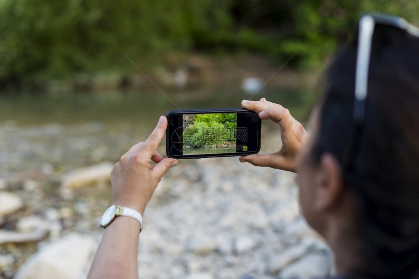 摄影女师用手机在自然界拍照外部天聪明的图片