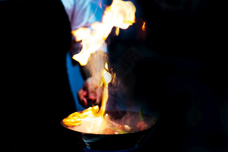 厨师在房炉灶的煎锅中用火焰做饭蔬菜刀气体图片