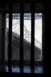 罗本透过监狱窗户的阴暗和景象窗上栅栏与墙只有铁丝网圈的眼线象征着囚犯没有自由这代表着倒钩拉根非洲背景