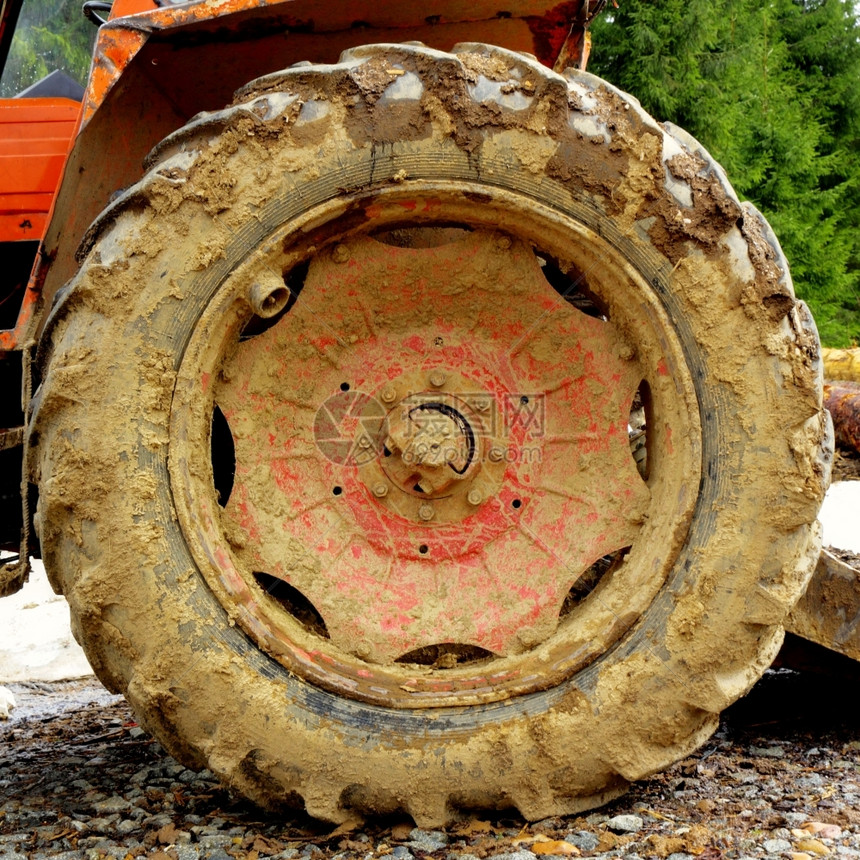在森林泥土的铁轨上工作后用肮脏的拖拉机轮红色车图片