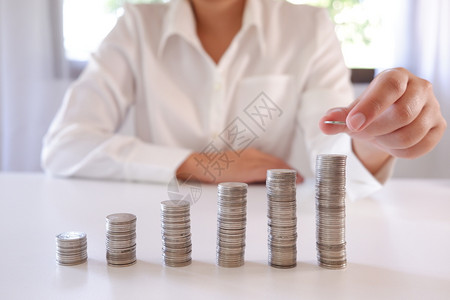 商业界人士将硬币放置在增加的硬币堆叠上成功公司的通货膨胀背景图片