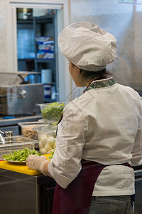 快速地白色的女厨和帽子在餐馆准备蔬菜盘子图片