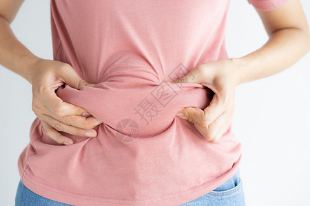 脐疝重量腰部牛仔裤妇女将自己的腹部脂肪和纤维素粘在白色背景上的妇女体重减瘦前的妇女形成健康的胃肌肉概念以及背景