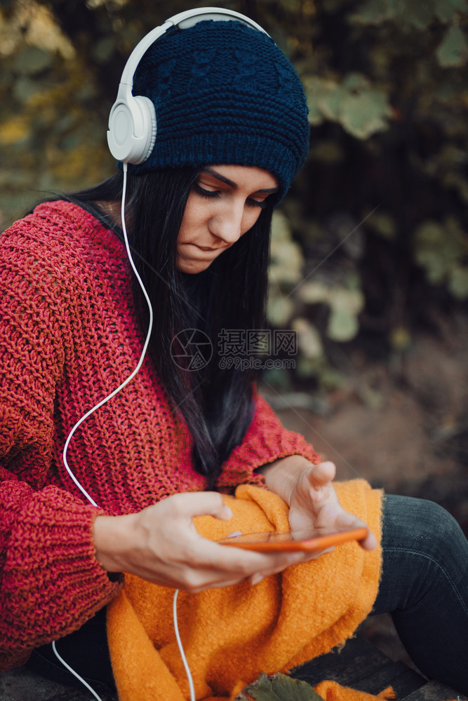 女孩年轻子在森林里用耳机监听音乐甜的牛仔裤图片