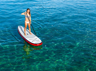 海一个美丽的女人在阳光明媚的日子里练习划桨户外女孩背景图片