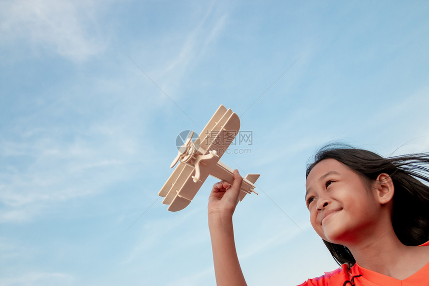 快乐的孩子玩具木机在日落的天空背景下游戏飞行员头盔图片